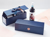 Blue gift box with a wine bottle and accessories on a light gray background