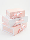 Set of three pink and white gift boxes with ribbons on a light background